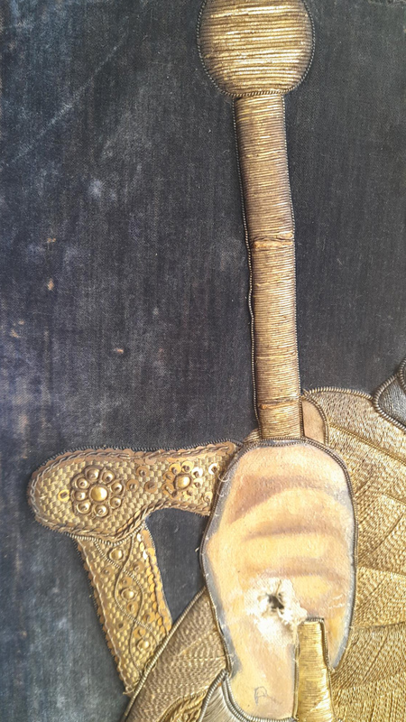 Dettaglio della mano che impugna il bastone e della seconda lacuna perforante del ricamo di Menelik II.